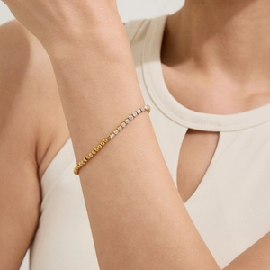 Detailaufnahme des goldenen Perlenarmbands mit Tennis-Design am Handgelenk getragen