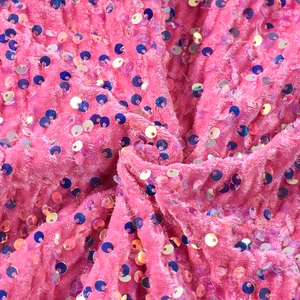 Gros plan d'un tissu en velours rose avec paillettes irisées montrant un drapé doux