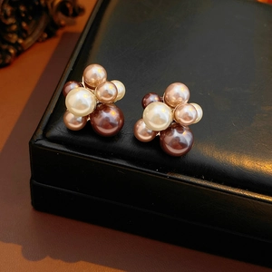 Détail de boucles d'oreilles perles en grappe aux tons blanc, champagne et chocolat sur cuir