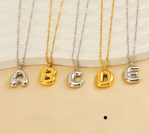 Detailed view of 3D bubble letter pendants in gold and silver polished stainless steel