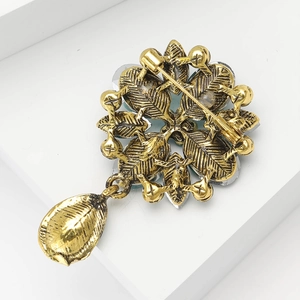 Detail showing back of vintage gold brooch with safety pin clasp and metal texture