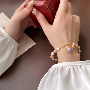 Détail d'un bracelet en perles colorées avec chaîne dorée et pendentif violet sur un coffret