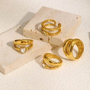 Minimalist double layer gold stainless steel rings with zircon stones on stone background