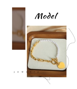 Detail view of gold horseshoe chain bracelet with pearl beads and heart pendant