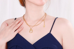 Detail of layered gold stainless steel necklace with heart pendant on a model