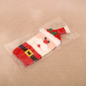 Detail of knitted Santa Claus wine bottle cover featuring beard and belt in clear packaging