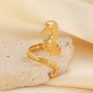 Detailed close-up of golden seahorse wrap ring on mineral stone with satin background
