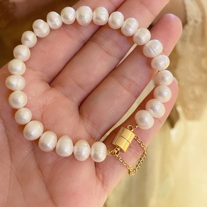 Detail of freshwater pearl bracelet featuring gold magnetic clasp and safety chain