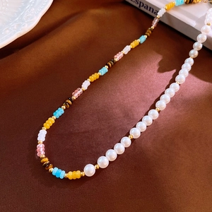 Detail of beaded necklace featuring white pearls, colorful beads, and gold spacers