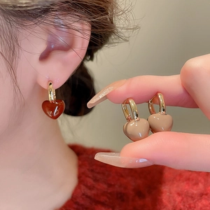 Détail des boucles d'oreilles cœur vintage dorées avec une finition en émail brillant
