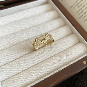Detail of a triple-layered gold star ring with zircon accents on a beige jewelry cushion