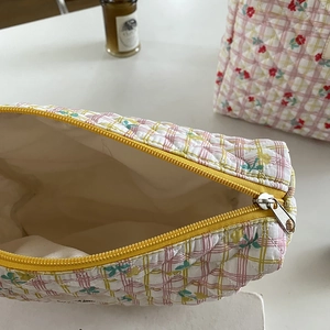 Detail of floral quilted cosmetic bag featuring yellow zipper and cream lining