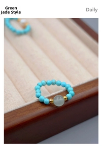 Macro shot of turquoise beaded ring with green jade bead and golden metal accents
