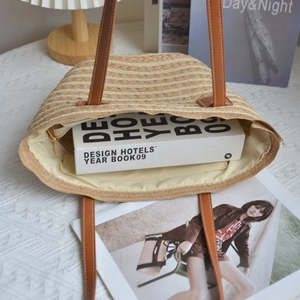 Detail view of woven straw tote bag open on a table showing interior storage capacity