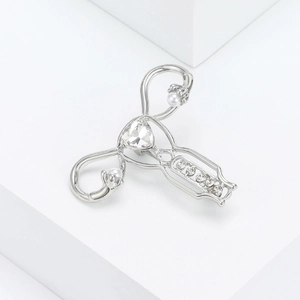 Macro shot of silver uterus brooch featuring sparkling crystals and white pearl accents