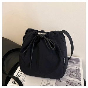 Detail view of the black drawstring bucket bag with side label on an aesthetic magazine