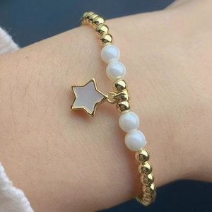 Detail of beaded star charm bracelet featuring gold beads and white star pendant