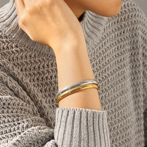 Stacked gold and silver striped bangles with crystal inlay on a model's wrist