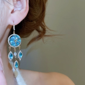 Detailed close-up of crystal earrings with blue stones and sparkling diamond pavé