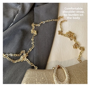 Close-up of champagne gold evening clutch featuring a rhinestone ring buckle and metal chain