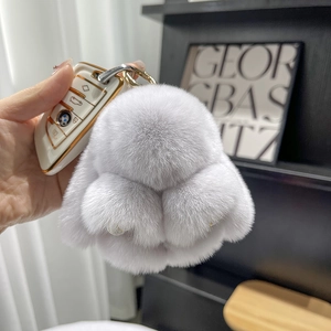 Close-up of a fluffy light grey rex rabbit fur keychain with a gold-tone metal ring