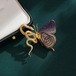 Exotic golden snake and purple butterfly brooch with gemstone on dark green velvet