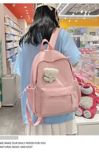 Detailed view of pink school backpack with a cute teddy bear plush charm and side pockets