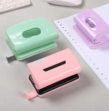 Close-up of pastel green, purple, and pink hole punchers on an office desk setting