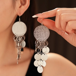 Detail showing oversized silver metal round sequins fringe earrings on a model