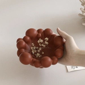 Brown bubble-shaped resin tray for jewelry storage being held to show actual size