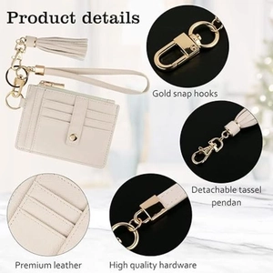 Detail of cream leather card holder with gold snap hooks and detachable tassel pendant