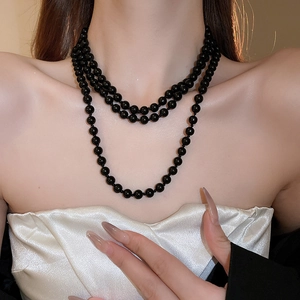 Close-up of triple-layered black faux pearl necklace on elegant model for a layered look