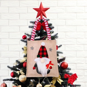 Christmas gnome burlap gift bag with plaid hat hanging on a decorated festive xmas tree