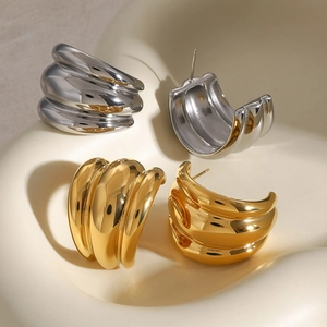 Textured gold and silver croissant dome earrings on minimalist display pedestals