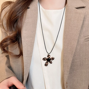 Detail of leopard print flower pendant necklace worn on a khaki blazer jacket