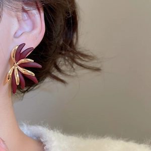 Detail of 18k gold plated flower stud earrings with burgundy petals on a model