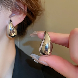 Close-up of polished silver teardrop earrings showing metallic texture on a model
