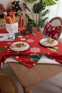 Close-up of red Christmas tablecloth with green trees and white snowflake patterns