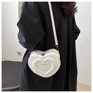 Detailed view of white heart-shaped crossbody bag with gold Fashion & Bag lettering