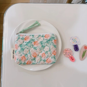 Detail of quilted floral coin purse with zipper, pastel flower print and side woven label