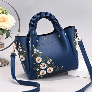 Blue PU leather handbag with floral embroidery, woven handle and gold hardware detail