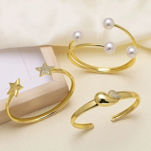 Three elegant 18k gold plated open bangles with pearls and star designs on silk