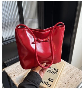 Détail du sac sous le bras en cuir rouge avec finition brillante et nœud élégant