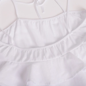 Detailed texture of white tiered ruffle dress with delicate spaghetti straps and linen fabric