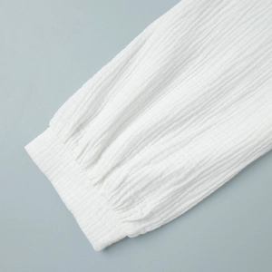 Dettaglio macro del polsino elasticizzato e del tessuto bianco stropicciato della camicia