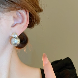 Gros plan détaillé d'une élégante boucle d'oreille en perle grise et zircons dorés