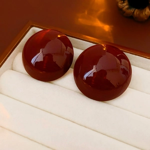 Dettaglio di orecchini a perno tondi rosso scuro vintage su scatola porta gioie bianca
