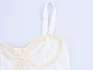 Detail of white dress showing braided rope pattern and adjustable metal buckle shoulder strap