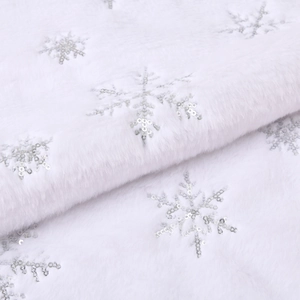 Detail of white faux fur Christmas tree skirt featuring silver sequin snowflake patterns