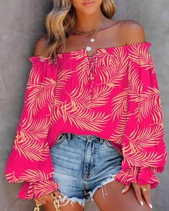 Detail of off-shoulder lantern sleeves on a rose red floral print blouse with palm patterns
